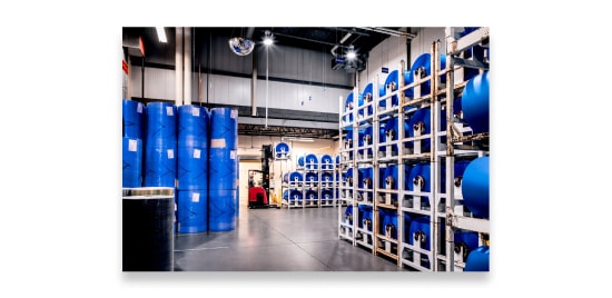 Warehouse with blue industrial rolls of film stored in large, tall racks.
